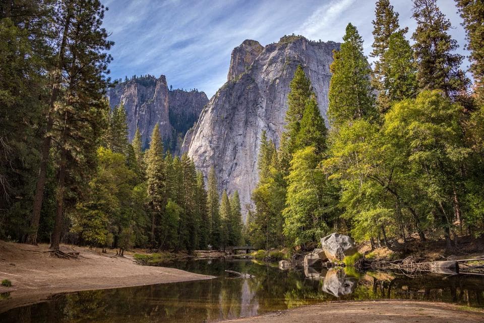 Forest valley with cliffs reflected in a river
